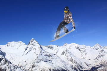 Fototapeta na wymiar Flying snowboarder on mountains. Extreme sport.