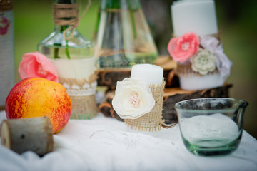 Wedding decor with wedding rings, peaches,  roses, candles and bottles  in style of a shabby chic. Decoration of a wedding photoshoot.  Details of a wedding decor.