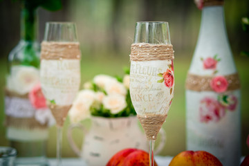 Wedding decor with wedding glasses in style of a shabby chic, bottles, peaches. Decoration of a wedding photoshoot.  Details of a wedding decor.