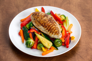Grilled chicken fillet, breast with cooked vegetable  on plates.