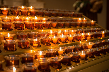 Prayer candles light up the darkness in a church.