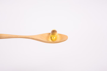 Omega 3 fish oil capsule on wooden spoon