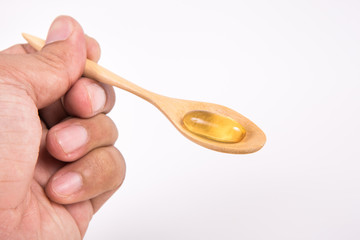 Omega 3 fish oil capsule on wooden spoon