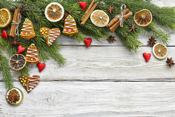 Christmas tree branch with gingerbread , cinnamon, hearts on wooden background 