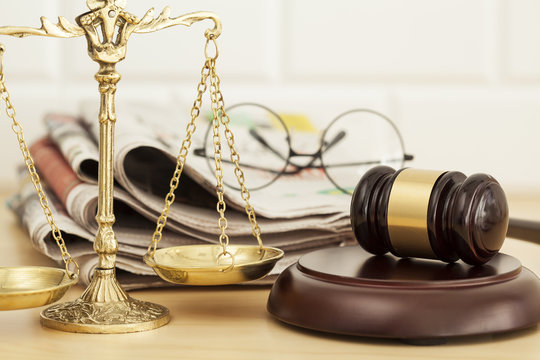 Justice scale with gavel, newspaper and eyeglasses