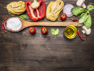 Ingredients for cooking vegetarian pasta with vegetables, a wooden spoon, herbs and butter on wooden rustic background top view close up border ,with text area