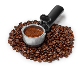 Obraz premium Coffee machine filter holder with ground coffee on coffee beans heap isolated on white