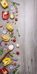 Ingredients for cooking raw pasta with tomatoes, pepper, a wooden spoon, salt, oil, pine nuts and herbs on wooden rustic background top view border ,place for text