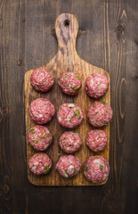 meat balls with herbs and onions on a cutting board on wooden rustic background top view close up