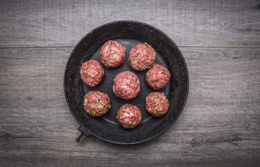 meat balls with herbs and onions in a vintage pan on wooden rustic background top view close up