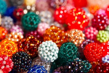 Woven colorful balls made of tiny glass seed beads, closeup with bokeh