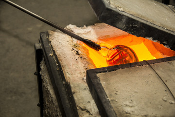 Handmade figure of melted glass, a glass blower working molten glass on a rod 