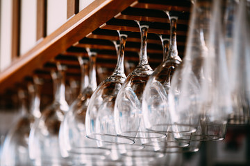 Empty glasses for wine above a bar rack. Hanging wine glasses in