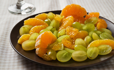 Chopped grapes with mandarins on table