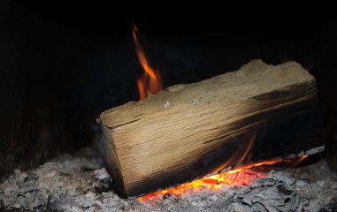 Burning wood with gray coals on black background