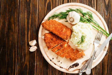 
meat with garnish , chicken cutlets in breadcrumbs , boiled mashed potatoes with herbs , garlic and spices on a wooden background