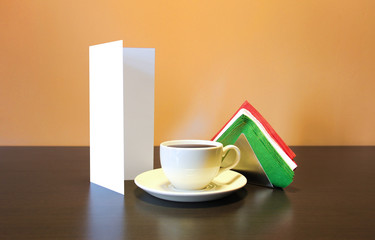 Blank booklet brochure flyer stand near the coffee cup and napkins on wooden table. Nice mock up to show shows showing restaurant cafe cafeteria identity. Menu flier cappucino latte italia napkin.