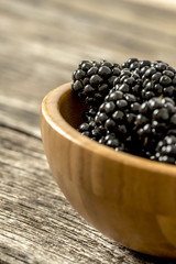 Fototapeta na wymiar Closeup of delicious ripe blackberries heaping in a wooden bowl
