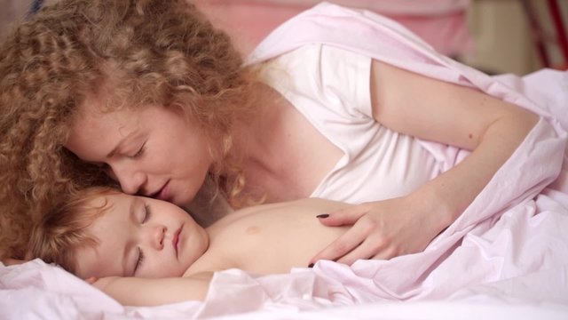 gentle kiss and words of love from a young mother sleeping child