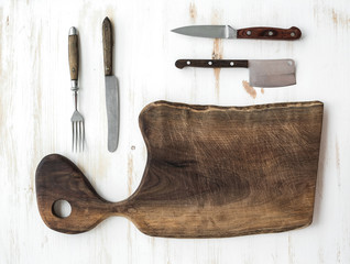 Kitchen-ware set. Old rustic chopping board made of walnut wood, knives, fork on a white background