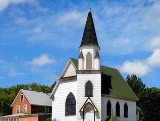 Fototapeta na wymiar Church of Christ in Hancock, Michigan is white with green roof. Dome is also green with cross finial on steeple.