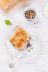 Traditional pie with salmon, spinach and basil on a white table. Top view.