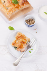 Traditional pie with salmon, spinach and basil on a white table. Top view.