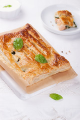 Traditional pie with salmon, spinach and basil on a white table