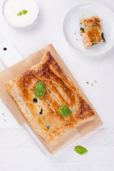 Traditional pie with salmon, spinach and basil on a white table. Top view