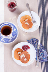 Pumpkin pancakes with honey, nuts and jam in a white plate on a table. Top view.
