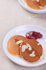 Pumpkin pancakes with honey, nuts and jam in a white plate on a table. Closeup.