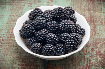 Blackberries in a bowl on wooden table