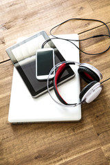 Digital devices and Headphones on a wooden Desktop.