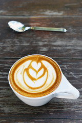 cup of latte art coffee on wooden background