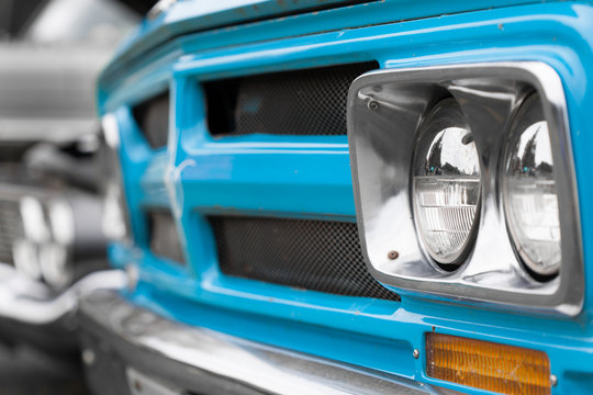 Close-up of right headlights of a blue shiny classic vintage car