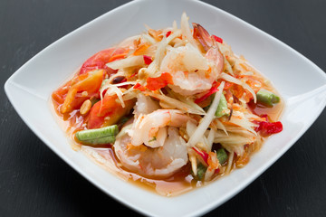 Green papaya salad (Som Tum) with shrimp on black background