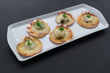 Baked parmesan scallops on black background