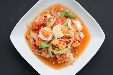 Green papaya salad with salted egg on wood table