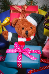 Teddy bear with colorful gifts for Christmas and spruce branches
