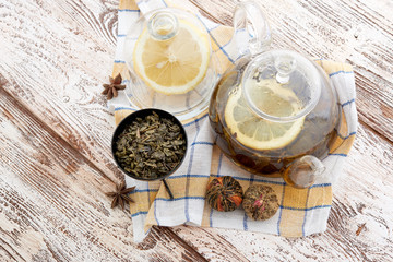 Fototapeta na wymiar Ripe lemon, cinnamon and fruit drink in glass teapot on wooden background