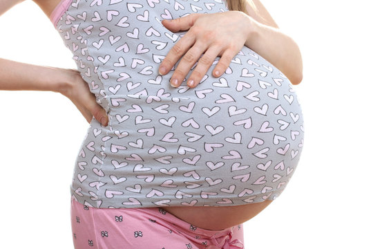 a pregnant woman in pyjamas clings to the waist on a white isolated background