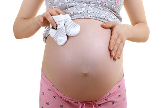 a pregnant woman in pajamas holding little socks isolated on white background