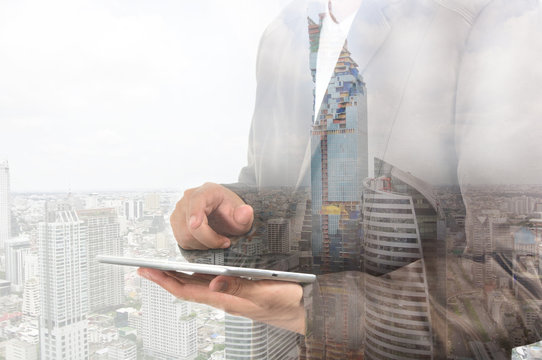 Double exposure of city and business man using digital tablet