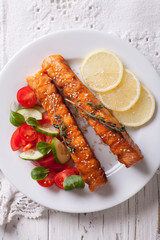 Grilled salmon with lemon and salad on a plate close-up. vertical top view

