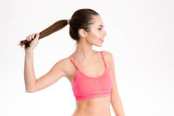 Profile of sportswoman in pink top holding up her ponytail