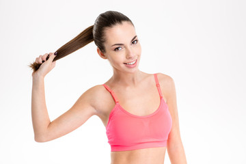 Fototapeta na wymiar Amusing cheerful fitness girl holding her long hair in ponytail