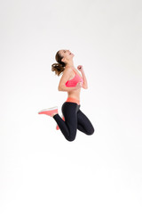 Fototapeta na wymiar Attractive excited fitness girl in sportwear jumping of joy