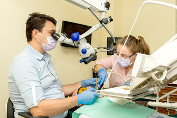 Dentist doing a dental treatment using microscope