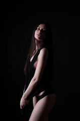 Sexy brunette tan girl with long hair over dark background, studio shot