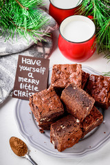  Brownie pieces with nuts on the plate and two cups of milk.